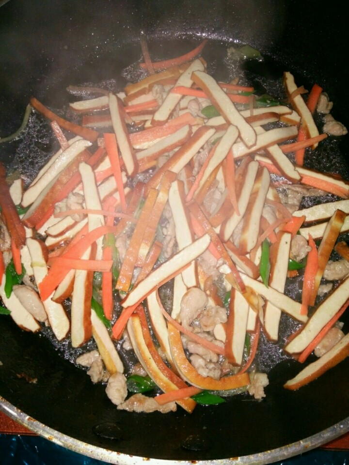 家常豆腐干两吃,放入豆腐干和胡萝卜,煸炒,加少量温水,加盐,翻炒一会儿,让豆腐干入味。