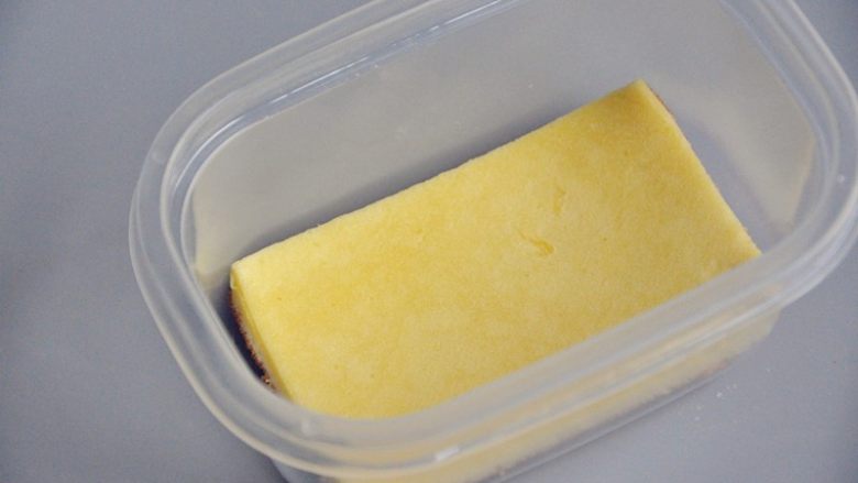 草莓奶油蛋糕盒子,出炉放至微温,烤网上放一张油纸,倒扣轻轻手动脱模,将蛋糕片切成和盒子一样大小。