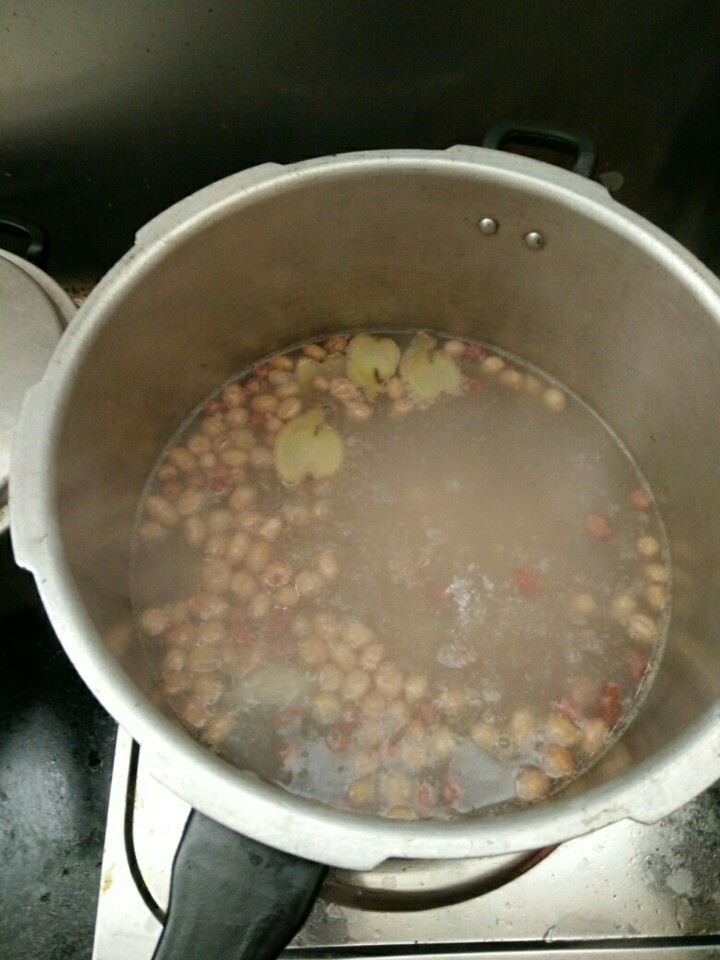 猪尾巴花生木瓜汤,加入花生,盖上盖子中火煲沸5分钟(我用的是高压锅,用沙锅或是其它锅的,水开后要煲15分钟)