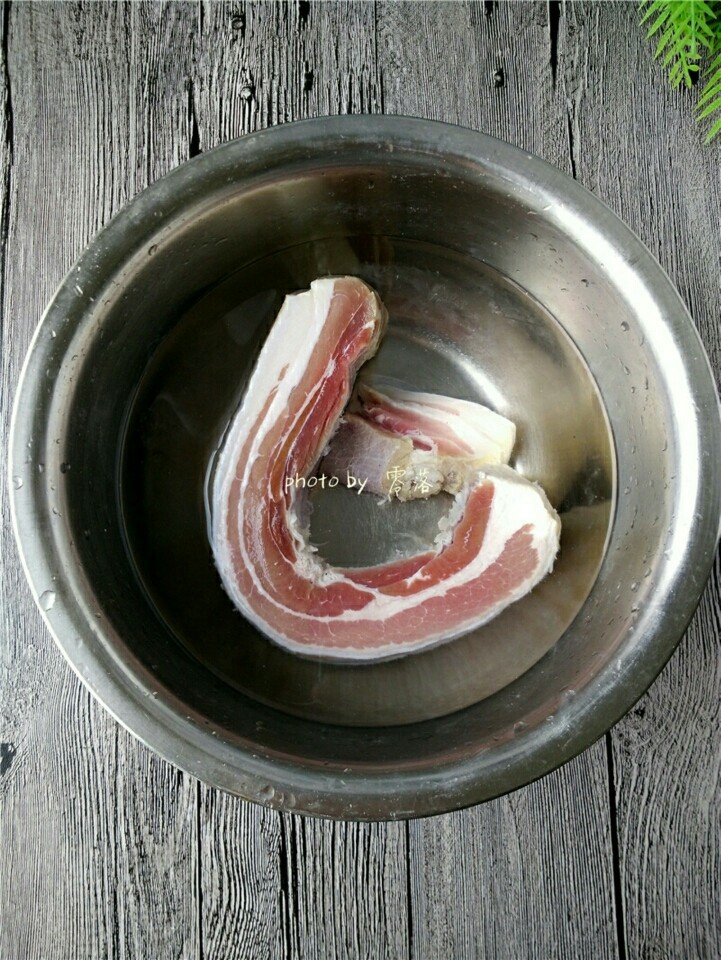 香煎腊肉,腊肉洗掉表面的盐粒,再用刀口刮洗肉皮部分;彻底洗净后,用清水浸泡片刻,去除多余的盐分;