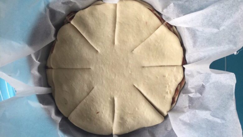 豆沙手撕花样面包,然后将面饼胚连同油纸一起放入圆形烤盘中,或者披萨盘都可以。