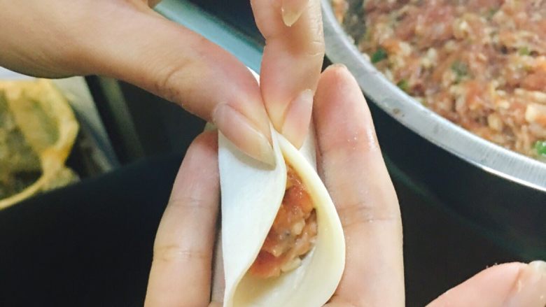 香菇青椒猪肉馅红油水饺,将饺子皮对折,并将中间部分捏实