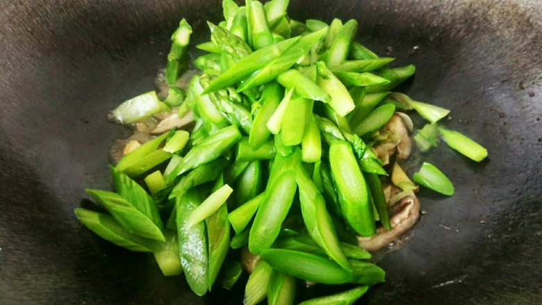 笋香肉段,将锅里的水烧干,下入焯烫好的芦笋,翻炒均匀。