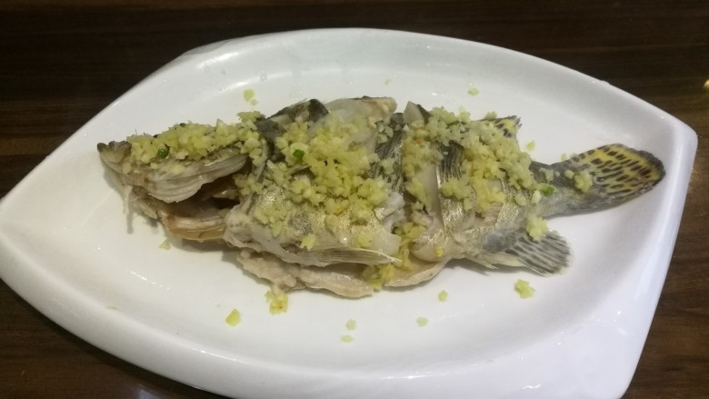 葱油桂花鱼,同时,在鱼身上均匀撒上姜、蒜。