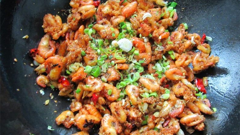 蒜香辣味虾,倒入虾翻炒裹上蒜泥味后关火,并倒入青蒜碎,洒上黑椒粒装饰即可出锅