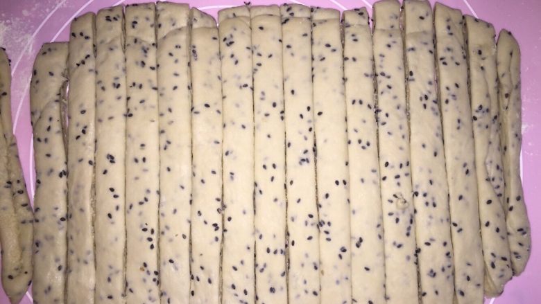 黑芝麻椰蓉面包棒,冷冻好的面团,用擀面杆擀长点,再修去四周,再均匀的切成条,不要太小条