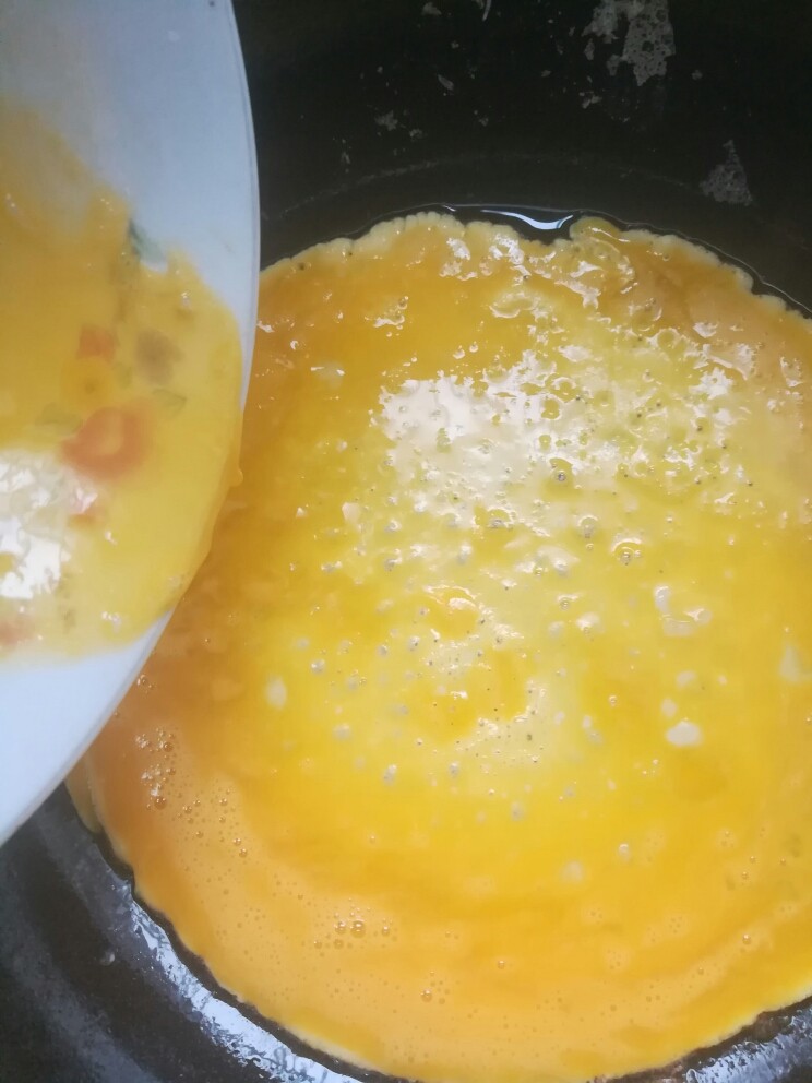 双椒火腿炒鸡蛋,锅烧热后开小火,倒入蛋黄,凝固后倒在熟食砧板上。