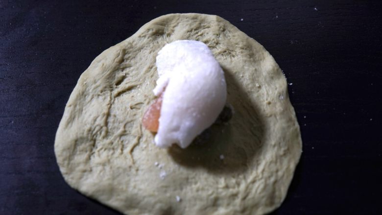 抹茶豆大福软欧,将小面团擀开排气,包入甘纳豆和糯米馅,收口朝下将缝口捏紧,将缝口朝下。