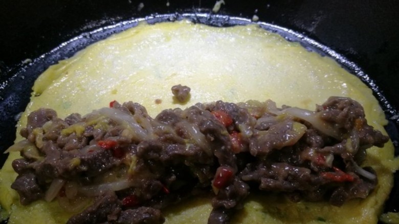 鸡蛋牛肉卷,煎1分钟后，鸡蛋饼翻面，加上先前炒好的牛肉白菜料，再煎1分钟，卷起来便可。