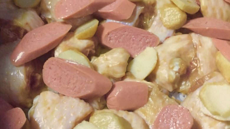 鸡翅鱼蛋香肠电饭煲焗饭,5~10分钟后打开电饭煲,把香肠鱼蛋也放下去,均匀铺平。