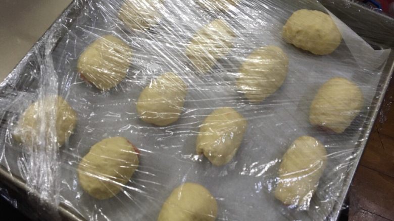 火腿面包,可以根据火腿肠大小,做处面包大小。拿出一小块面团,按平将火腿肠包在中间,口向下。弄完之后,盖上保鲜膜2次发酵,至1倍大,大概需要1个半小时