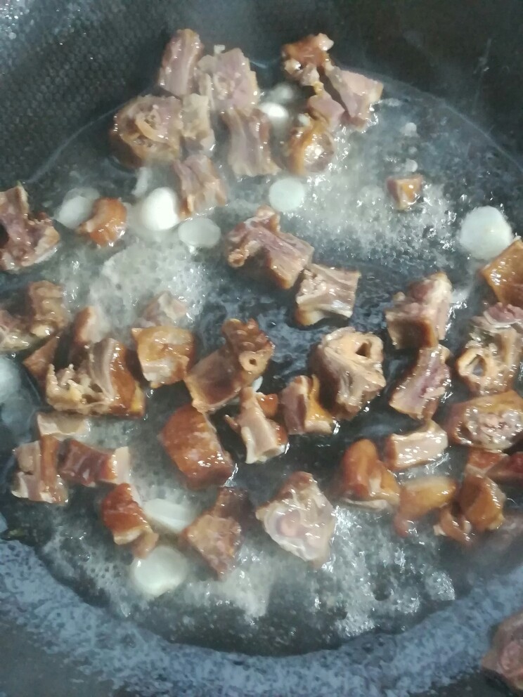 辣椒炒腊鸭,腊鸭连碗里的汤水一起倒入锅内,和蒜片一起爆香。