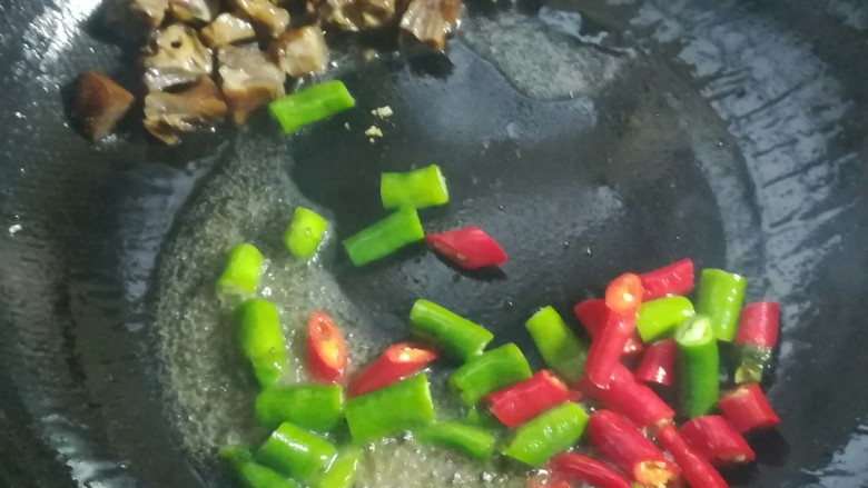 辣椒炒腊鸭,把鸭块扒在一边,下青红尖椒段大火炒半分钟。