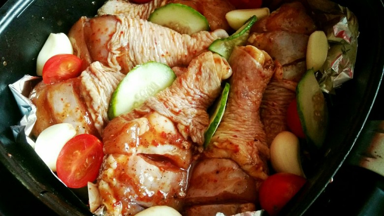 时蔬烤鸡腿(空气炸锅版),鸡腿铺在上面,周围点缀些圣女果,黄光片,大蒜等等,
