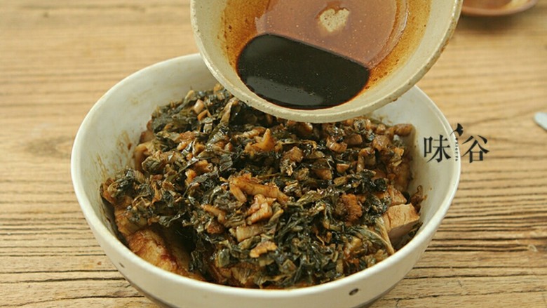 梅菜扣肉,炒好的梅菜铺在码好的肉片上面,淋上刚才配好的酱汁 。