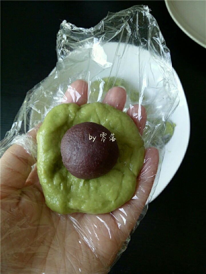 自制青团,戴上一次性手套(没有手套,也可裹保鲜膜),在上面抹点<a style='color:red;display:inline-block;' href='/shicai/ 406'>猪油</a>(或玉米油),取一小块面团,揉圆,压扁,包上豆沙馅儿;