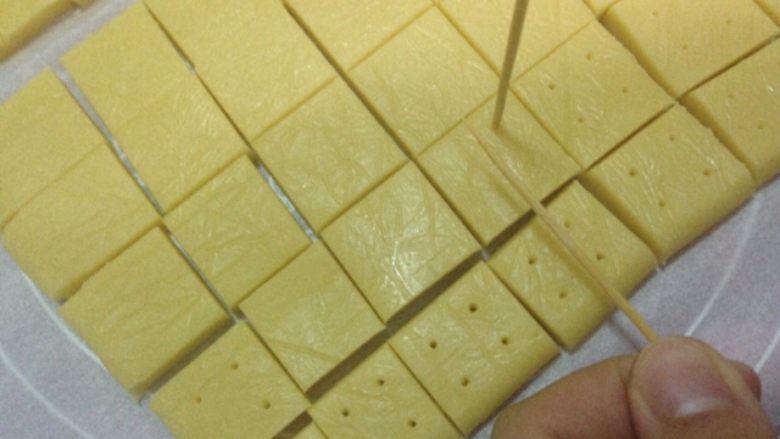 奶油奶酪小方,放入冰箱半小时后取出切小块,用牙签在方块上戳洞方便烤熟