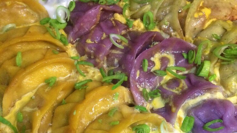 三色煎饺,取一个鸡蛋搅拌散淋在饺子上面,焖一分钟,待鸡蛋凝固成型,撒上葱花,继续盖锅盖焖半分钟即可出锅