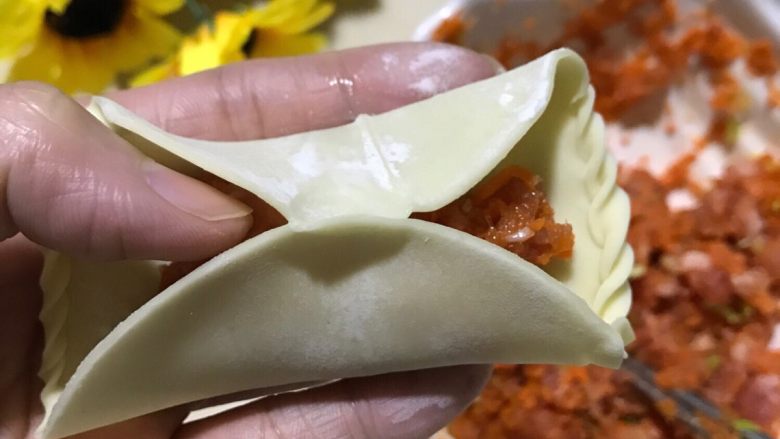 鸳鸯饺子,拿起饺子皮往中间捏紧,亲们要注意哦,我们买现成的饺子皮是很难捏紧的哦,要旁边放一点点水,稍微抹一下