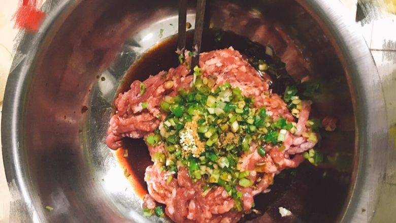豇豆猪肉馅水饺,凉水和食用油全部倒入。用筷子顺一个方向快速搅拌,直至肉馅呈棉絮状
