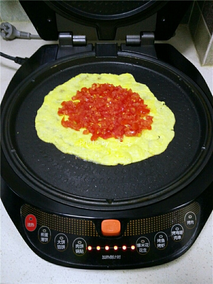 西红柿鸡蛋披萨,蛋液稍稍凝固后,在蛋饼中间铺上番茄丁;