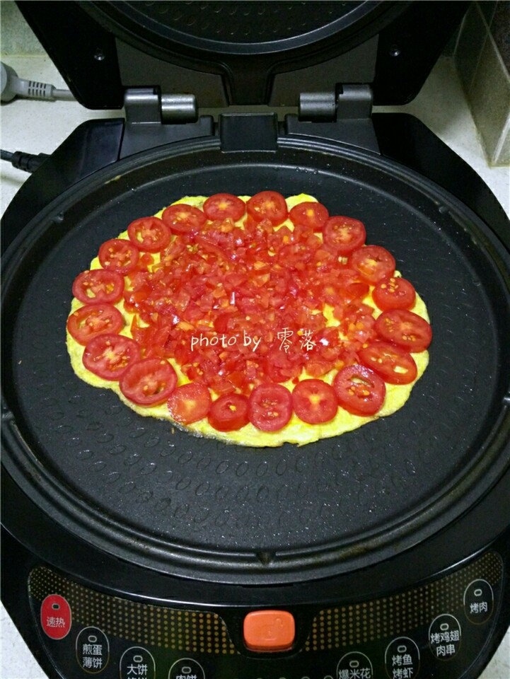 西红柿鸡蛋披萨,预热程序结束后,关闭电源;在蛋饼四周铺上番茄块;