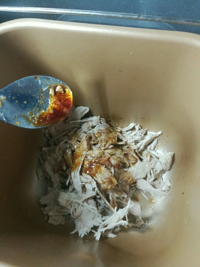 自制肉松,将肉丝倒入面包机中,淋上味汁,用筷子稍微搅一下,让肉丝均匀粘着味汁。