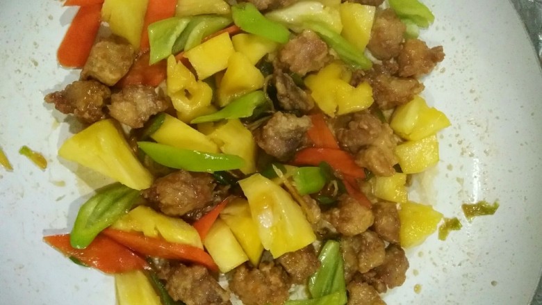 家常菠萝咕咾肉,剩下少量汤汁时，放入菠萝和青椒，翻炒，令其沾上汤汁即可出锅。