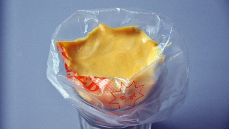 蛋黄饼干,将一次性裱花袋套在一个杯子上,倒入面糊。