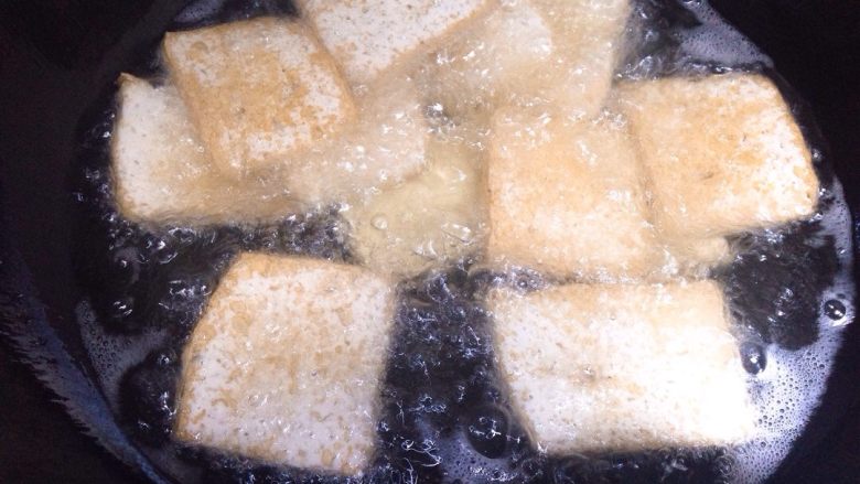 家常豆腐,将切好的豆腐片下入油锅炸制。
