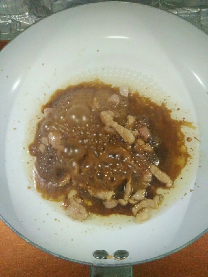 家常红烧芸豆,热锅凉热,煸炒肉丝,肉炒至白色,倒入生抽,煸炒着色。