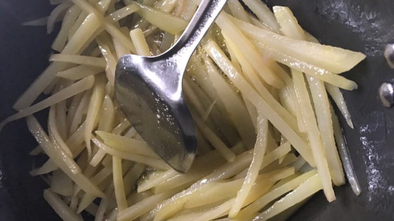 土豆丝炒肉末,第四步:锅洗干净,再次起火烧干锅,加入适量油,再放入洋葱翻炒,然后把土豆都捞起来放进锅里,不停的快速翻炒。