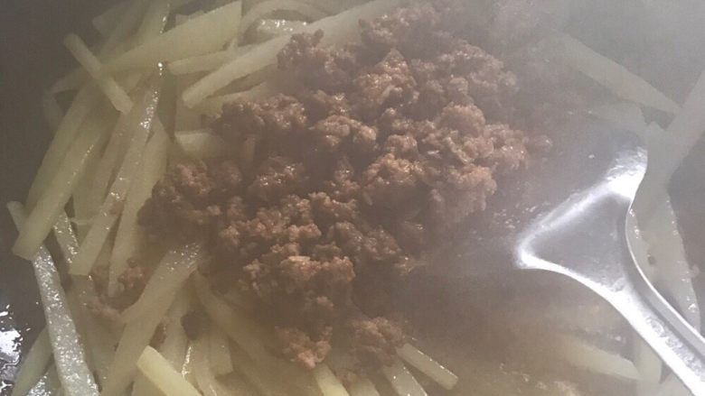 土豆丝炒肉末,第五步:土豆丝翻炒几分钟后,把炒过的肉末倒进去继续翻炒一分钟,然后倒入一碗清水,用炒菜铲翻几下,盖锅盖,等水沸腾几十秒后,再放半勺豆瓣酱翻炒,最后加入适量醋,几滴少量酱油,继续翻炒一分钟左右,就可以出锅了。