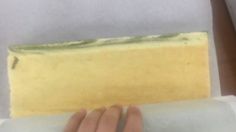 烫面抹茶蛋糕卷,另取一张油纸覆盖,把蛋糕翻过来,轻轻卷起