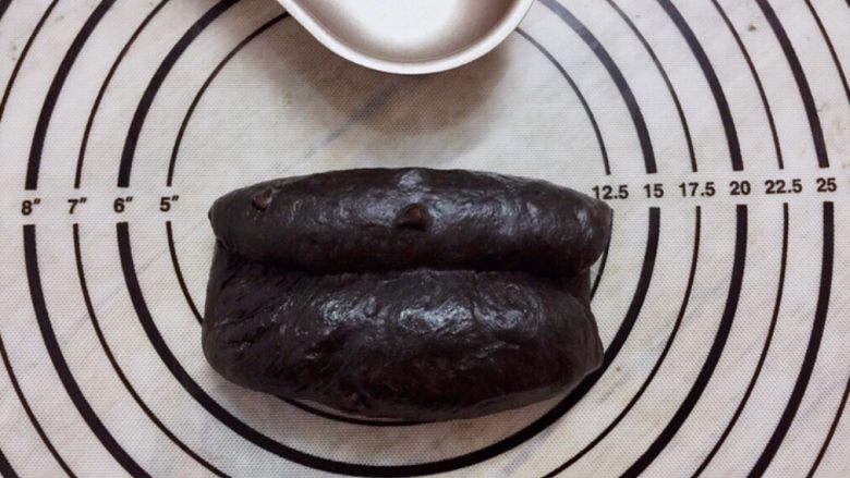 黑可可热狗包,取小份面团,擀成椭圆形,两边中间卷起来,收口捏紧,搓成橄榄型
