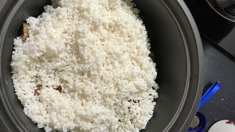 手抓饭(改良版),先把炒好的羊排和菜放入电饭锅,然后把泡好的大米放入(只放大米),然后把刚刚高压锅里面的羊排汤倒入电饭锅,汤没过米饭,搅拌一下,开始蒸米饭