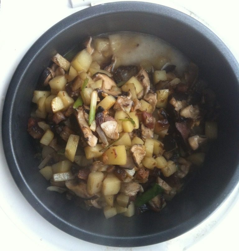 腊肉香菇土豆煲饭,将炒好的食材平铺在电饭锅泡好的大米上按煮饭步骤