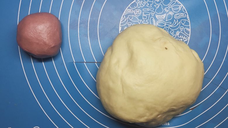 面包超人小餐包,取出发酵好的面团,用擀面杖或者手揉排气。取20克面团与红曲粉混合揉匀。把剩下的面团分16份,保鲜膜松弛15分钟,揉成光滑面团间隙的放到烤盘上。红色面团分48份,用作面包超人的鼻子和脸颊。