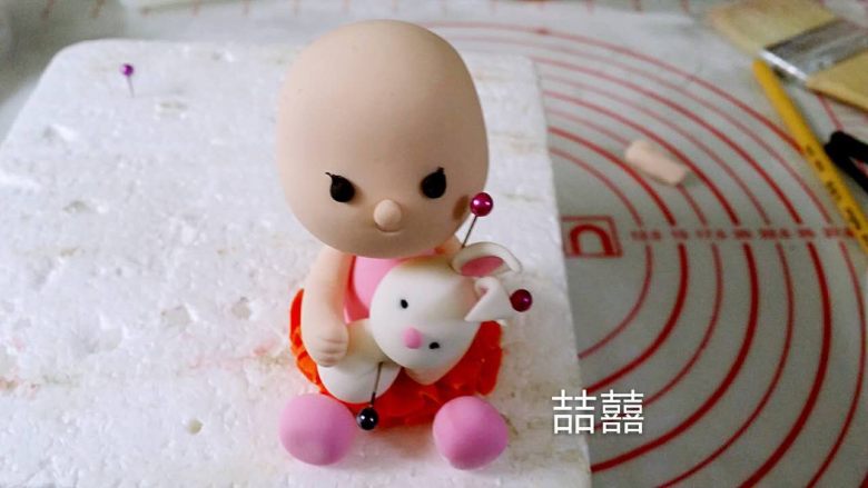 翻糖蛋糕--树桩上的小女孩儿,中间丢了几张图。搓一个小水滴型做兔子的身体,用做小孩儿头的方法坐兔子的头,再粘上耳朵,贴在小孩儿身前,再做出手臂抱的动作,然后搓4个小球做兔子的四肢