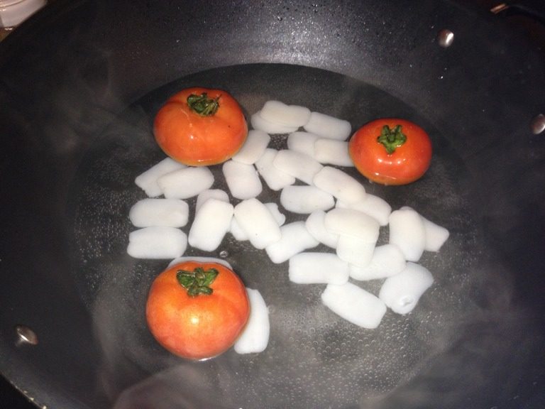 番茄炒年糕,如图然後再加入已經切好十字的番茄,在過程中不時番一下番茄,讓他的皮更好的分離。