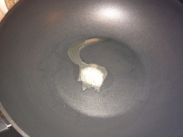 番茄炒年糕,如图把鍋燒紅下一點油,然後下2勺鹽。
