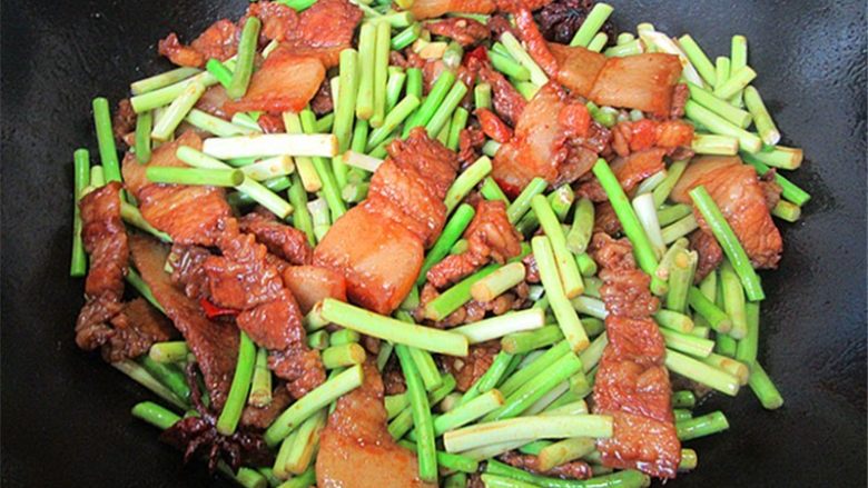 五花肉炒蒜薹,焖至肉质紧凑汤汁浓稠,放入蒜薹翻炒一分钟