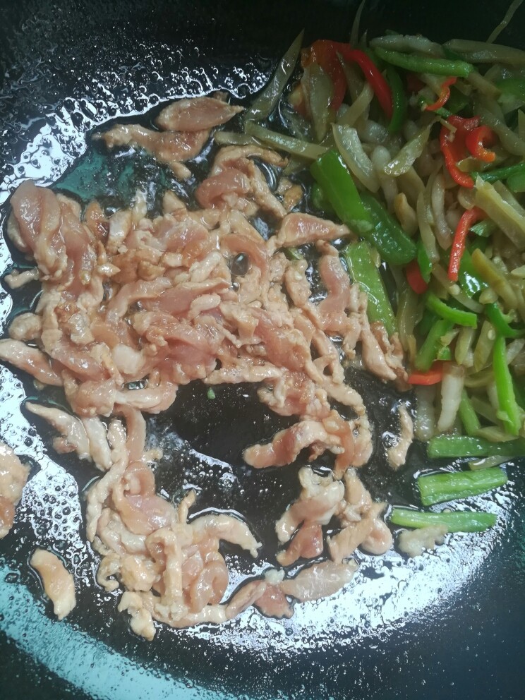 榨菜肉丝,把辣椒和榨菜扒在一边,下瘦肉丝,撒盐翻炒至七成熟。