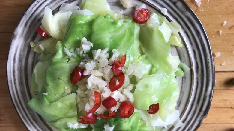 炝拌手撕包菜,焯好的包菜捞出摆盘子里,上面洒上蒜末、辣椒