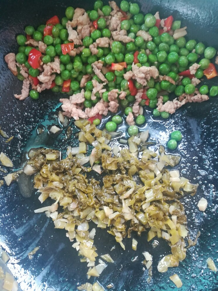 酸菜肉沫炒豌豆,把炒过的食材扒在一边,倒入挤干的酸菜单独炒半分钟。(为防止肉沫炒老)