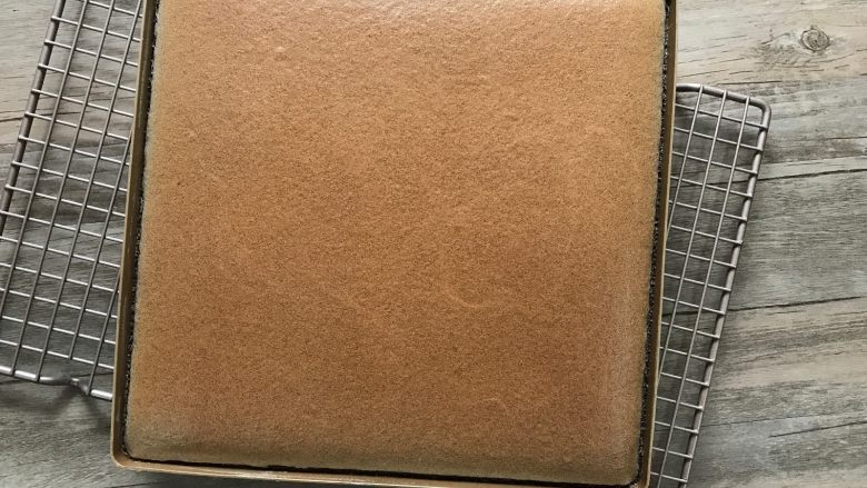 黑米戚风蛋糕卷,出炉震下模,蛋糕表面不是太烫时,烤网上垫张干净的油纸,将蛋糕倒扣在油纸上。