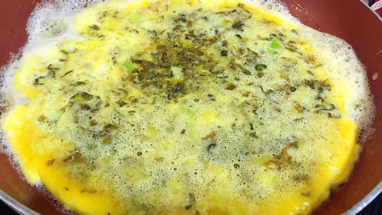 梅干菜煎蛋,平底锅注入油烧五六成热,改小火,倒入蛋液,均匀铺在锅底,小火慢煎到蛋液基本凝固,可以随意晃动锅底;
