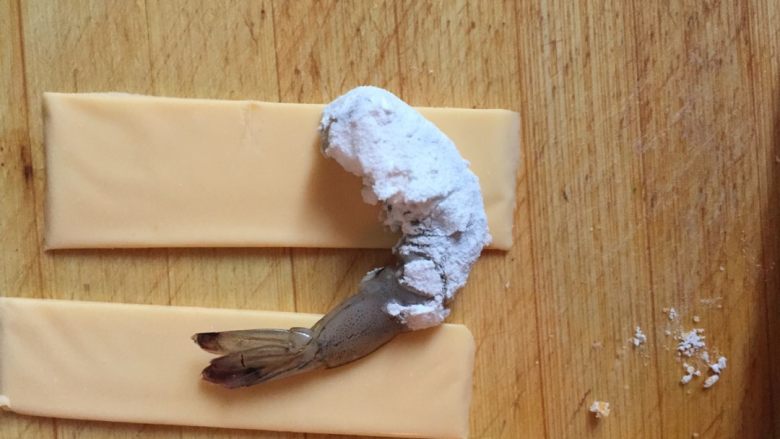 芝士虾球,将腌制好的虾用淀粉包裹,然后将其中四分之一片的奶酪片包裹住虾身部分。如果固定不住,可以尝试用牙签戳中固定。