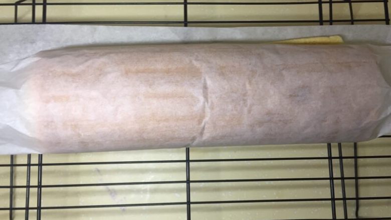 肥厚肉松卷,撕掉上面的油纸，先趁热卷一下，再铺开。这样夹馅儿的时候比较容易卷。