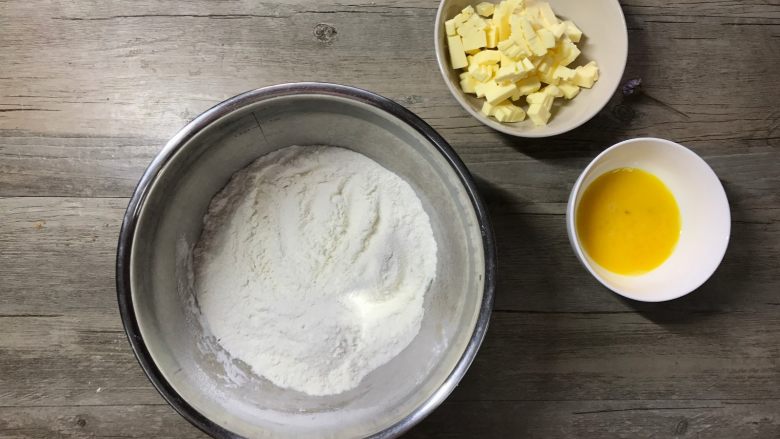 肉桂苹果派,先制作派皮:低筋粉加糖粉和盐过筛后入容器,黄油切成小丁软化。